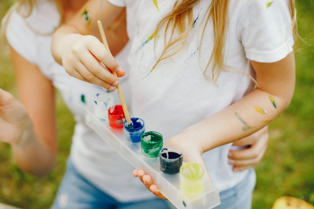 A little girl and her nanny painting with watercolours